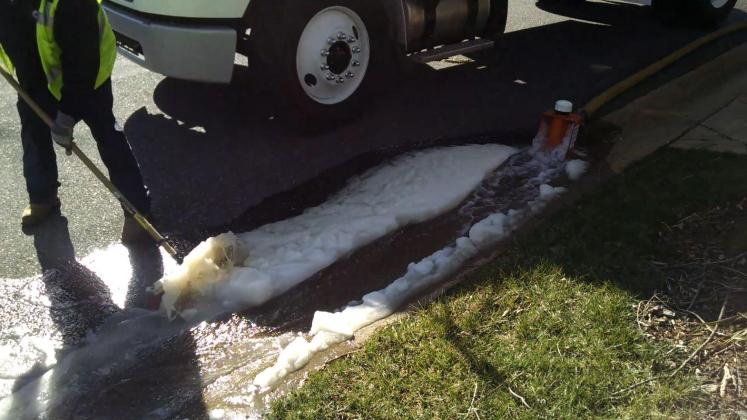 Workers sweep the dirty slush into a storm drain. (David Boraks/WFAE)