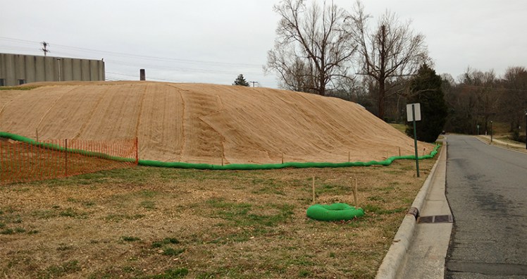 Workers cut down trees and shrubs then installed a plastic liner, soil and a fiber mat cover on this slope near the former Carolina Asbestos plant in Davidson. Last fall, environmental officials found asbestos running off from the hill. (David Boraks/ WFAE)